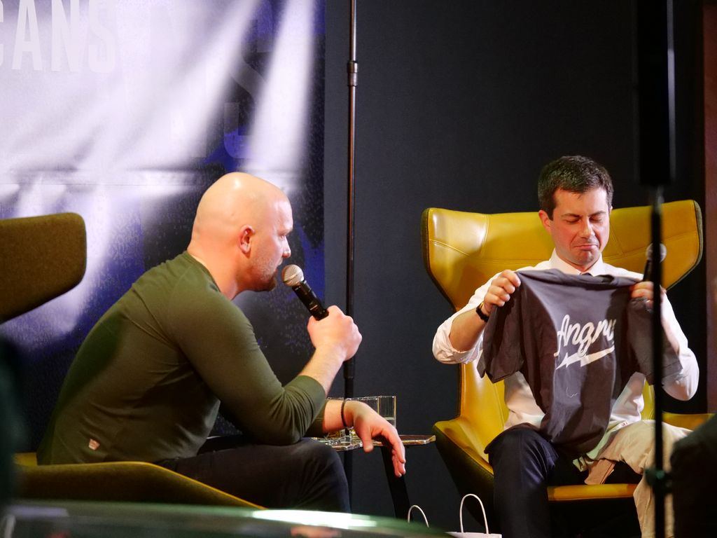 Pete Buttigieg is handed a shirt on stage in New York